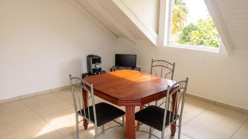 a dining room with a wooden table and chairs at Appartement confortable à Capesterre, 40 m², jardin agréable in Rabi