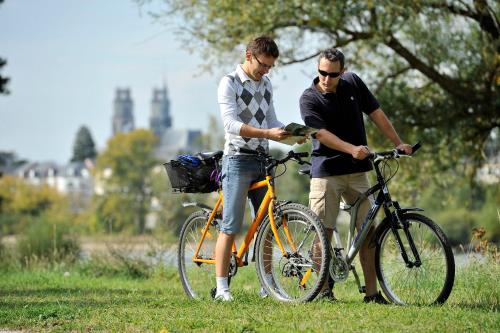 two men standing next to a bike in the grass at Camping de Montlouis-sur-Loire in Montlouis-sur-Loire