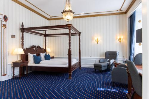 ein Schlafzimmer mit Himmelbett und Stuhl in der Unterkunft Hotel Phønix Aalborg in Aalborg