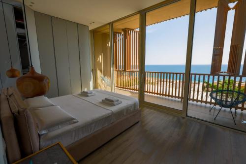 a bedroom with a bed and a balcony with the ocean at Vila IL SOLE GREEN COAST in Palasë