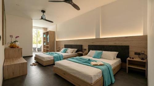 a bedroom with two beds with blue and white sheets at Nala Inn in Fulidhoo