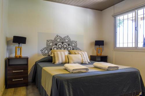 a bedroom with a bed with two lamps and a window at Monte Aromas Casas en la Naturaleza Roldán in Roldán
