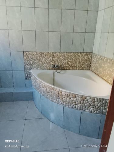 a bathroom with a bath tub with rocks around it at LINGE'S LODGE EXTENSION in Lusikisiki