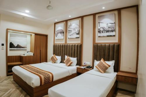 two beds in a hotel room with pictures on the wall at Hotel Asopalav in Junagadh