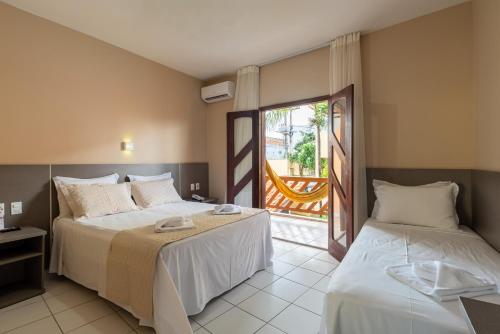 a hotel room with two beds and a balcony at Pousada D' Areia in Barreirinhas