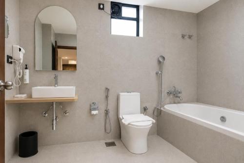 a bathroom with a toilet and a tub and a sink at Hotel Eagle Empire in Madgaon