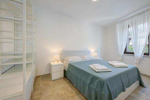 a white bedroom with a bed and a window at Al Casel - Appartamento Collina in Torri del Benaco