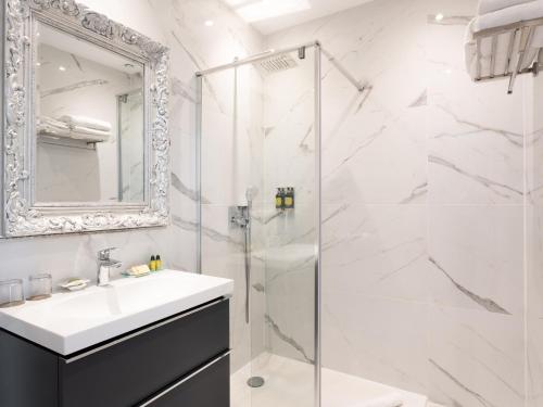 ein weißes Badezimmer mit Waschbecken und Dusche in der Unterkunft Hôtel La Villa Juan Beach in Juan-les-Pins