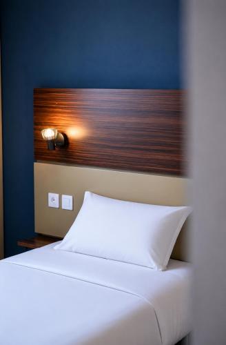 a bedroom with a white bed and a blue wall at Hôtel Le Palladior Voiron in Voiron