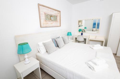 a white bedroom with a white bed and a blue lamp at Paradise Place Sifnos in Chrisopigi
