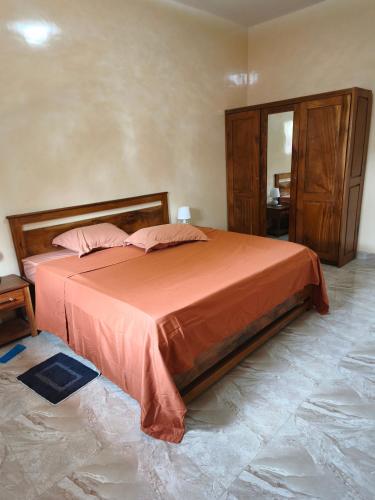 a bedroom with a bed with orange sheets and a mirror at Le Rivage de Sérénité in Sali Nianiaral