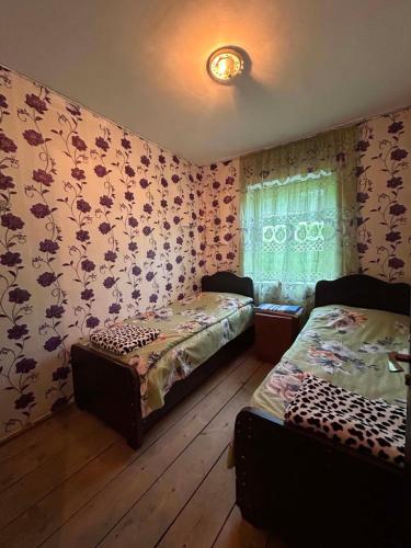 two beds in a room with floral wallpaper at Guesthouse Lika in Ushguli