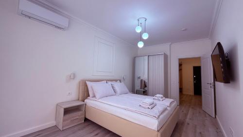 a white bedroom with a bed and a tv at Apartment OneClickRent 16 in Chişinău