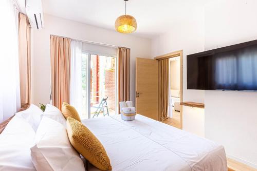 a bedroom with a large white bed with a flat screen tv at Dhermi's Icon Big 1BR Apt 10 in Dhërmi