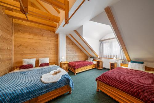 two beds in a room with wooden walls at Happy House Apartments & Sauna in Špindlerův Mlýn