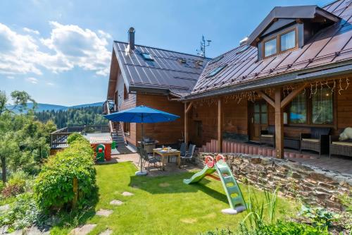 a house with a patio and an umbrella at Happy House Apartments & Sauna in Špindlerův Mlýn