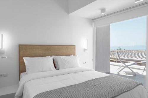 a white bedroom with a bed and a balcony at Twiins Studios by halu! - Next to Kallithea Beach in Kallithea Halkidikis