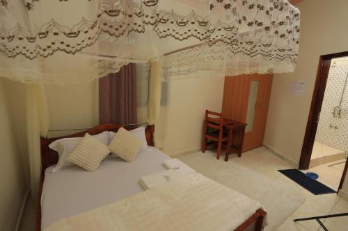 a bedroom with a bed with white sheets and curtains at Grand View Hotel in Fort Portal