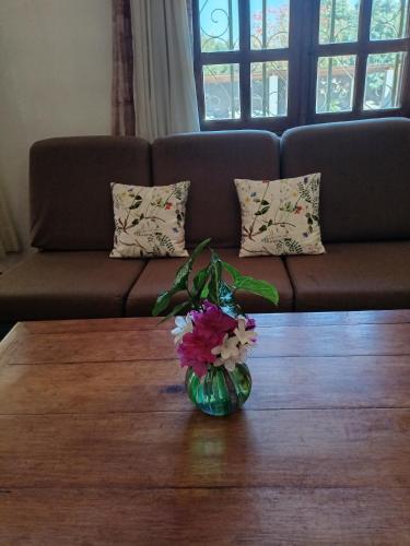 a vase of flowers on a table in front of a couch at Hôtel Mahavelo 2 étoiles in Antananarivo