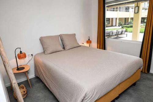a bed in a room with a large window at BEACH house in Westende-Bad