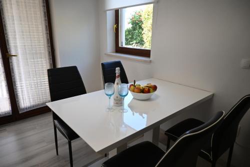 a white table with a bowl of fruit and wine glasses at Apartma Mija - XL in Kornić
