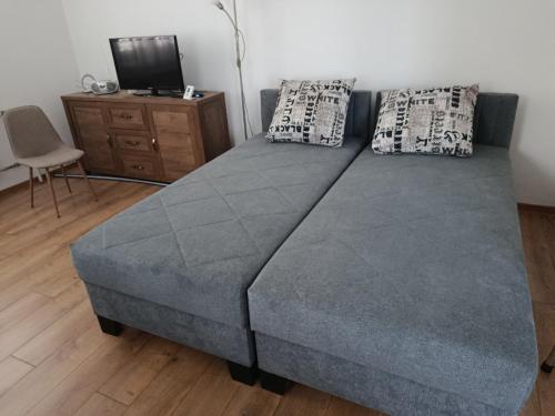 a blue bed with two pillows and a tv at Chalúpka Liptov in Lúčky
