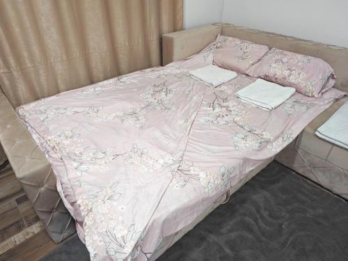 a pink bed with two towels on top of it at Apartmani Peric Bogatic in Bogatić