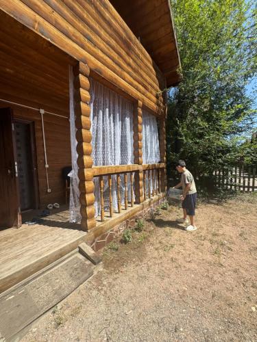 a man standing outside of a log cabin at Деревянный домик in Dolinka