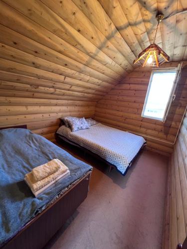 an attic bedroom with two beds in a log cabin at Деревянный домик in Dolinka