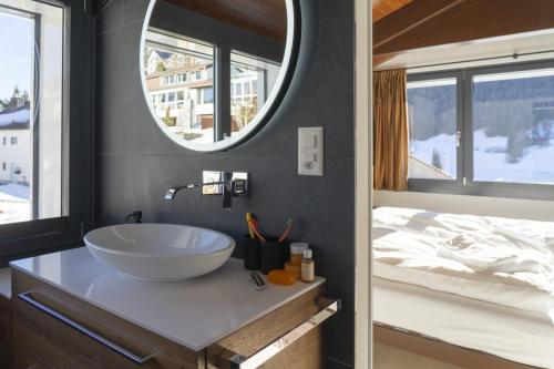 ein Badezimmer mit Waschbecken, Spiegel und Bett in der Unterkunft Alpstern in Wildhaus