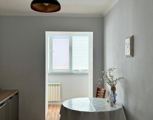 a dining room with a table and a window at Minimalist 2-room Apartment in Aktobe