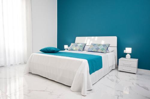 a bedroom with a white bed with a blue wall at Fantasia House in Marsala
