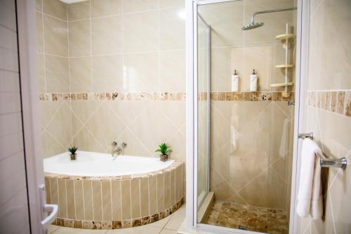 a bathroom with a shower with a tub and a sink at @47 Guest House in Gqeberha