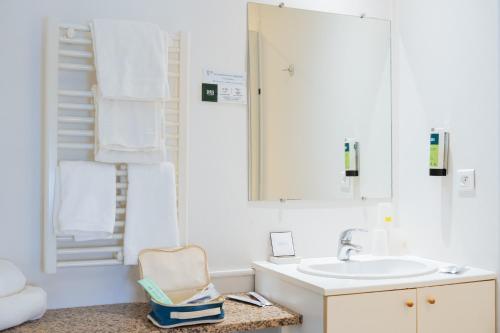 a white bathroom with a sink and a mirror at Logis Hôtel Restaurant Bellevue Annecy in Annecy
