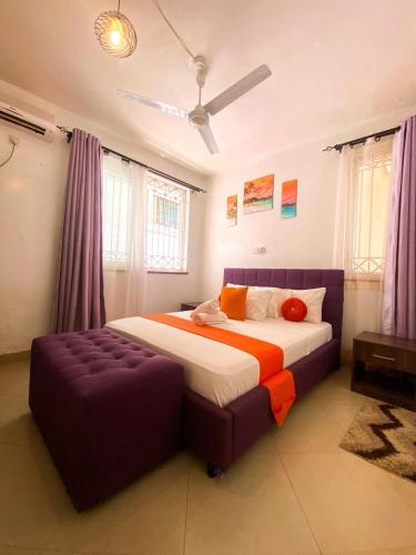 a bedroom with a large bed and a purple ottoman at jennies staycation in Mombasa