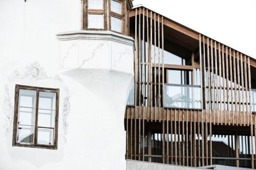 a building with a wooden staircase on the side of it at Hotel Weisses Kreuz in Malles Venosta