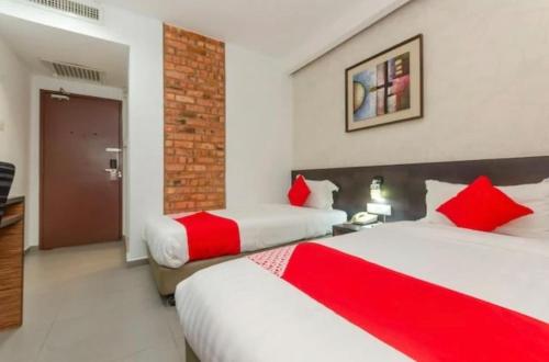 two beds in a hotel room with red pillows at Hotel Dream Nur Kota Syahbandar in Malacca