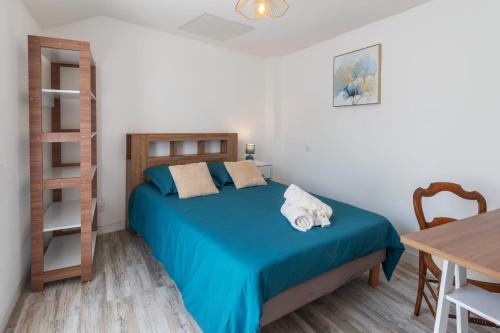 a bedroom with a bed with blue sheets and a table at Brise Lavalloise - Wifi - Centre Ville in Laval