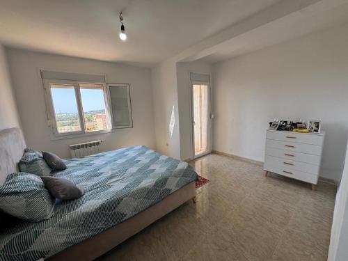 a bedroom with a bed and a dresser and two windows at Equipped apartment with elevator, sea view in Bordj el Bahri