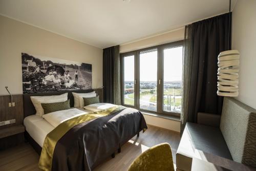 ein Schlafzimmer mit einem Bett und einem großen Fenster in der Unterkunft Hotel TheGreen ehemals Köln11 in Köln