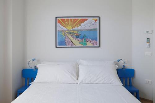 a bedroom with a white bed with a picture on the wall at VItruVIo POP in Fano