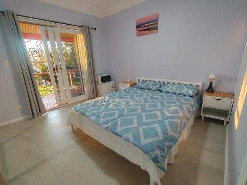 a bedroom with a bed and a sliding glass door at Sunset Nest No 1 in Sanctuary Point