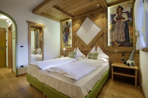 1 dormitorio con 1 cama grande y pared de madera en Hotel Azola, en Canazei