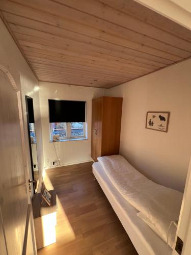a small bedroom with a bed and a television at Arctic Hostel Apartment in Qaqortoq
