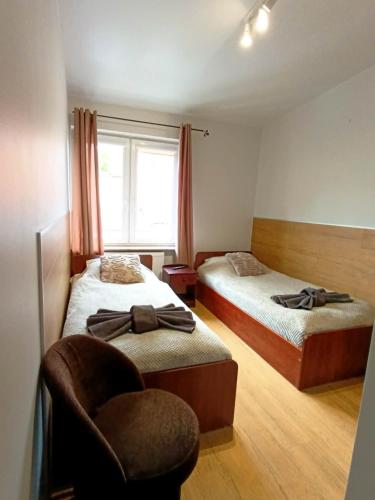 a bedroom with two beds and a chair and a window at Hotelik Kościerzyna in Kościerzyna