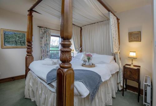 a bedroom with a four poster bed with white sheets at Mowhay Barn in Torpoint