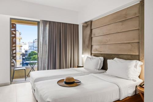 a hotel room with two beds with a hat on them at DOM Boutique Hotel in Heraklio