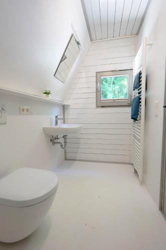a white bathroom with a toilet and a sink at Ferienhäuser Campingplatz in Kinding