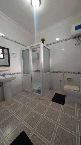 a bathroom with a shower and a toilet and a sink at Furaha House in Chukwani