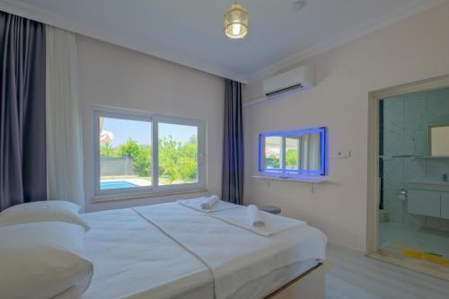 a bedroom with a large white bed and a window at Villa Ata Park Ortaca in Ortaca